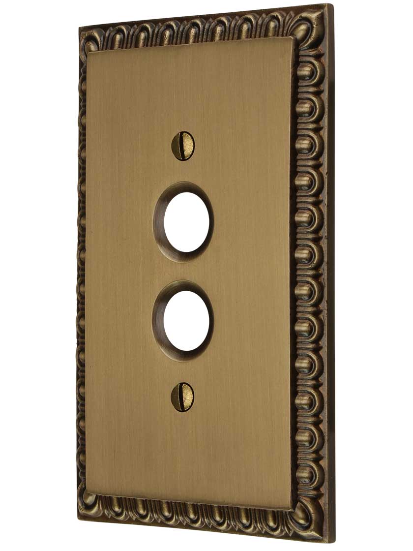 Ovolo Single Gang Push-Button Switch Plate in Antique Brass.